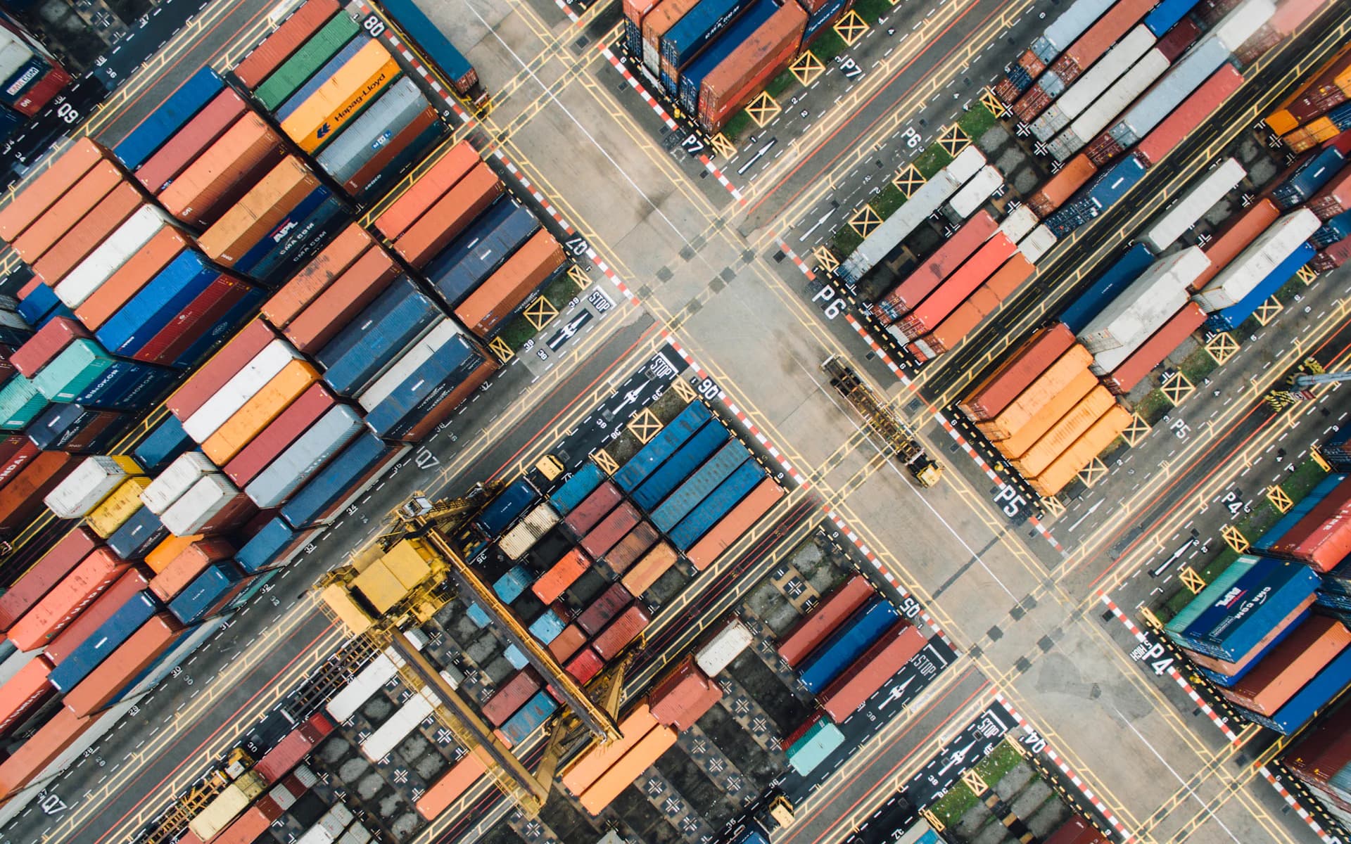 Aerial view of shipping containers and transport lanes at a cargo port.